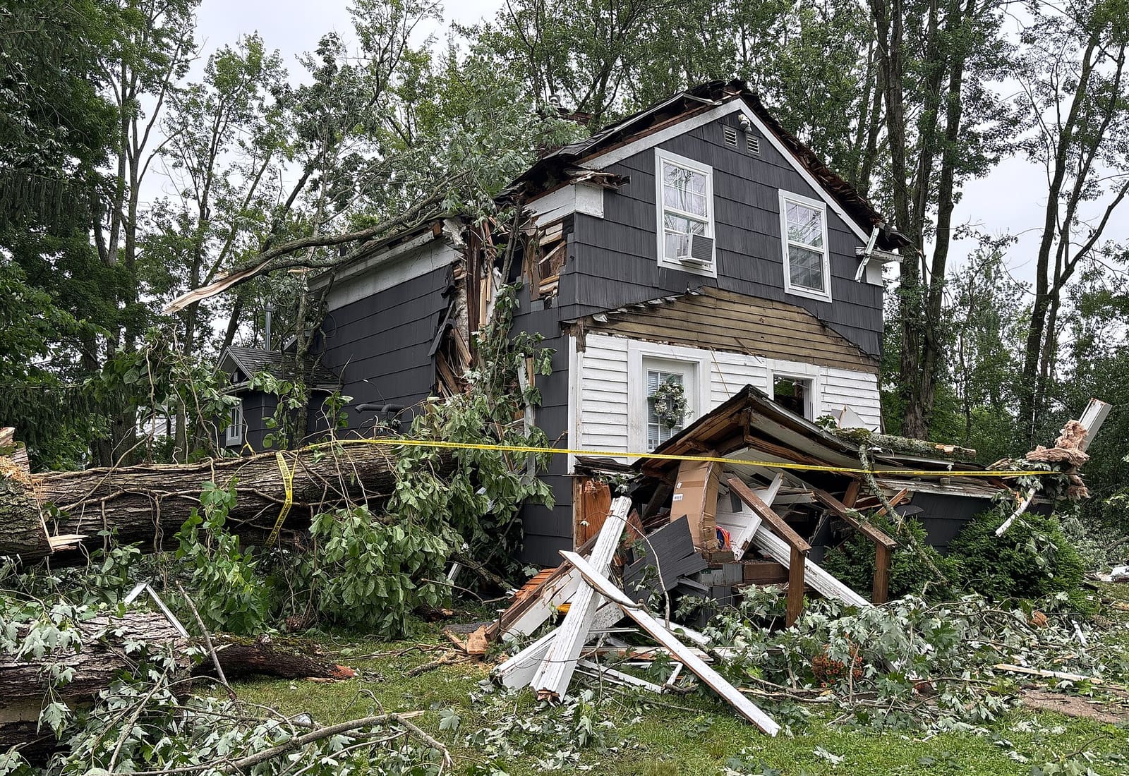 A storm-damaged tree resting against a house